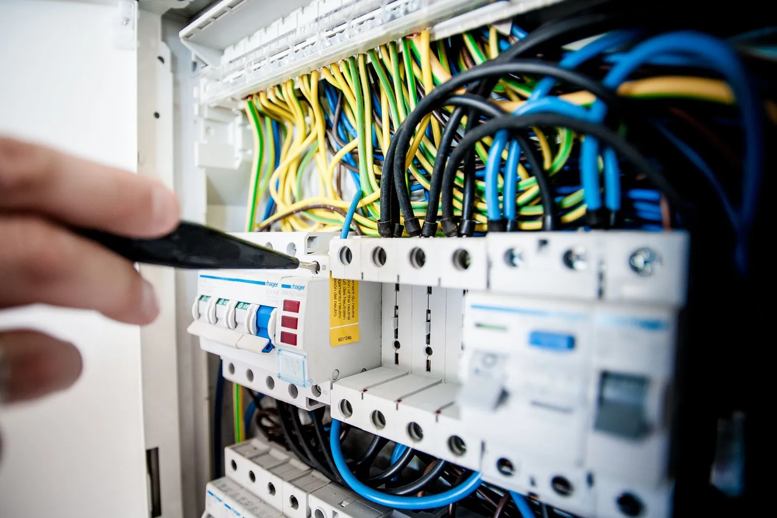An electrician works on an open switchboard