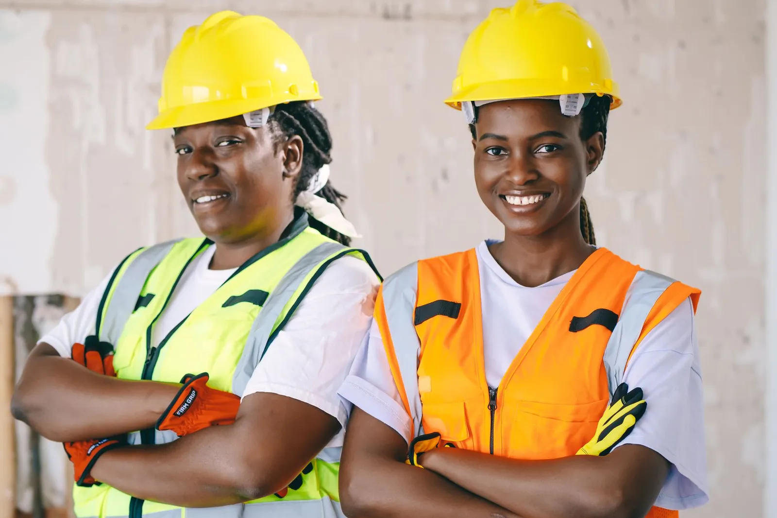 Dos mujeres con cascos amarillos y chalecos reflectantes en una obra